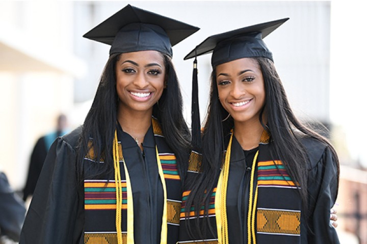 Two graduates wearing caps and gowns smiling